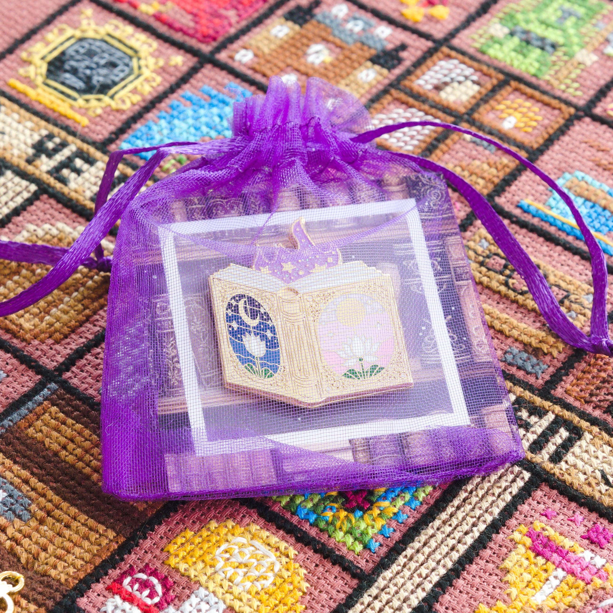 Fairytale book needle minder in a purple gift bag containing a card.