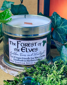 Tin candle called 'The Forest of the Elves. Soy wax candle with wooden wick sitting on a slice of rustic tree trunk. Ochre yellow background with ivy leaves and moss around the candle. A lantern with red orange glow is off to the side.