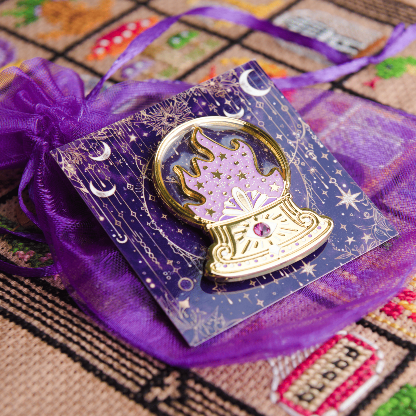 Crystal Ball needle minder displayed on a fantasy inspired card and resting on a purple organza bag.