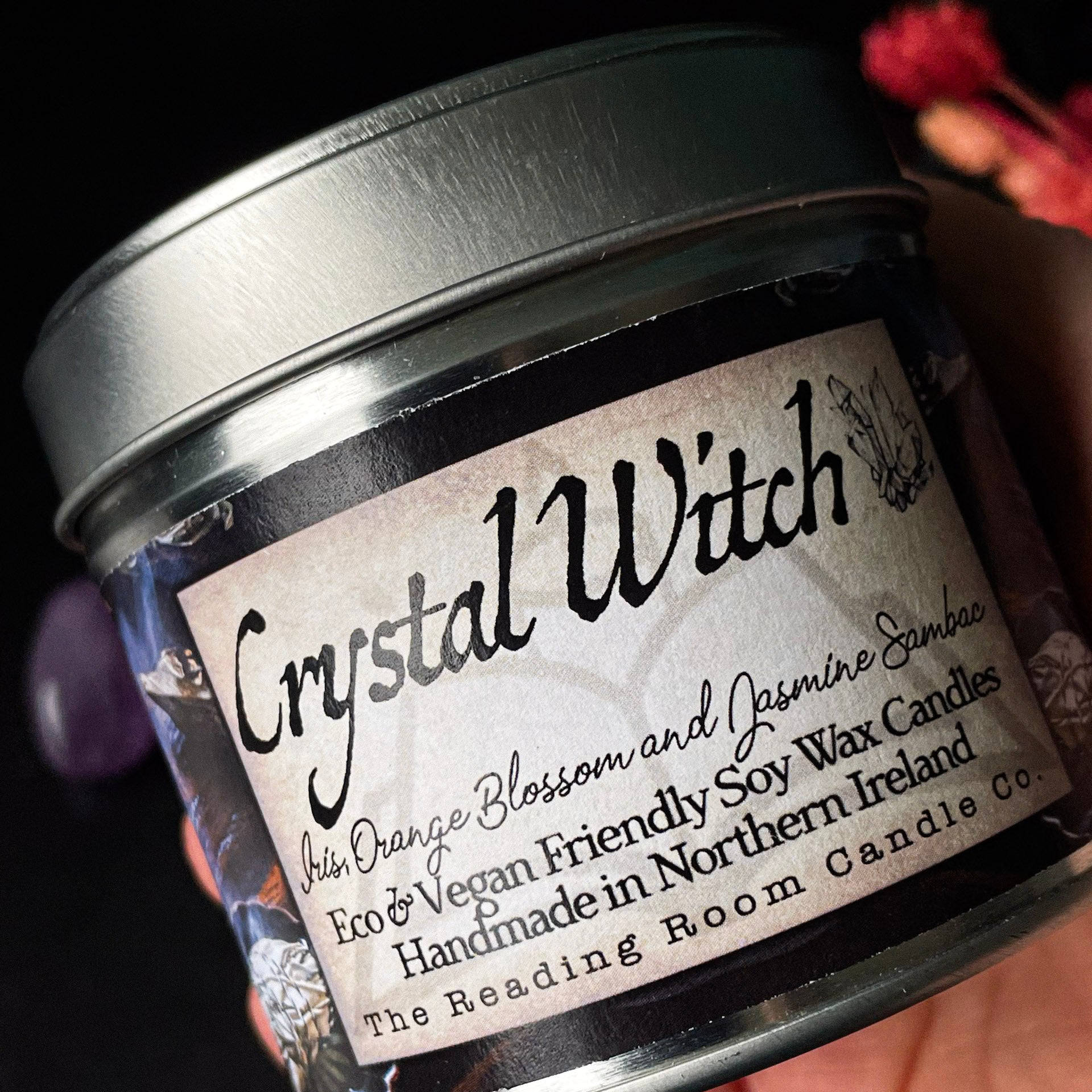 Jar of 'Crystal Witch' candle with a label on a dark background