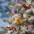 Wool felt mouse ornament dressed in a yellow coat, holding a gift and a bell, hanging on a Christmas tree with presents and berries.