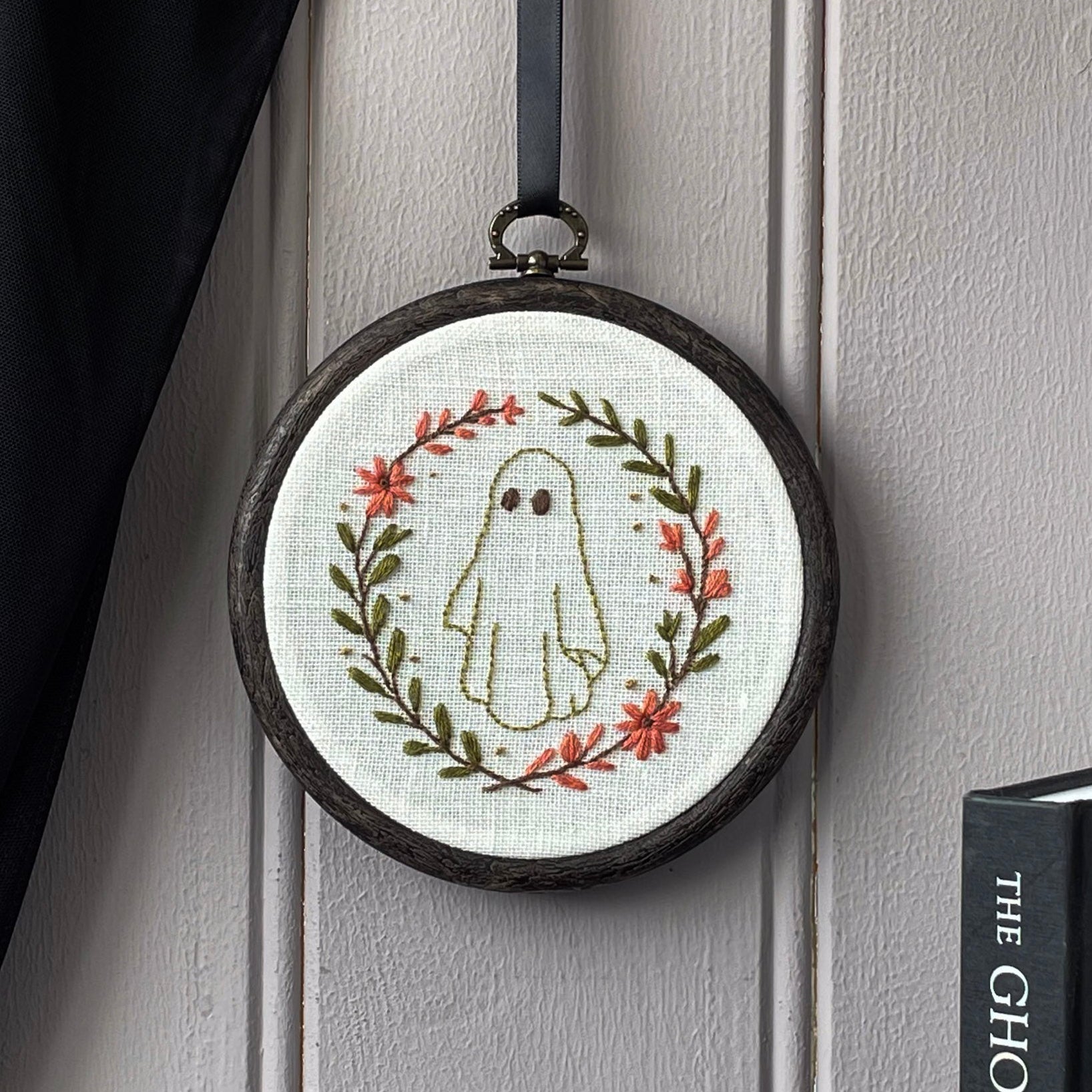 Embroidery hoop with ghost design hanging on a wall