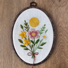 Embroidered floral design in a wooden hoop on a wooden surface