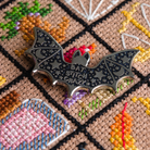 Halloween-themed cross-stitch pattern with a bat needle minder sitting on top.