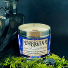 Handmade soy wax candle, titled Morrigan. Earthy with dark floral scent. The tin label shows images of ravens on a blue background. The ravens reflect the association with the goddess Morrigan.